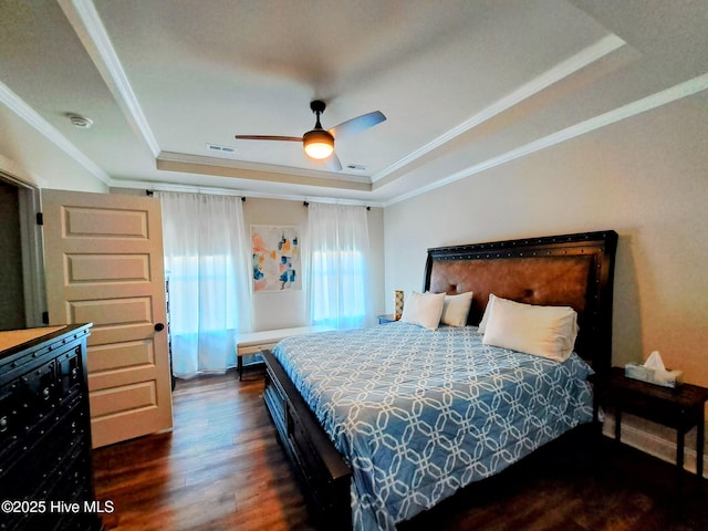 bedroom featuring visible vents, dark wood-style flooring, crown molding, ceiling fan, and a tray ceiling