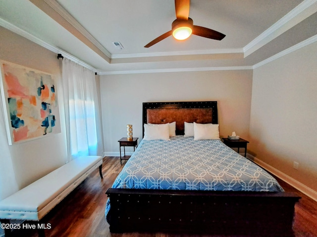 bedroom featuring wood finished floors, crown molding, visible vents, baseboards, and a raised ceiling