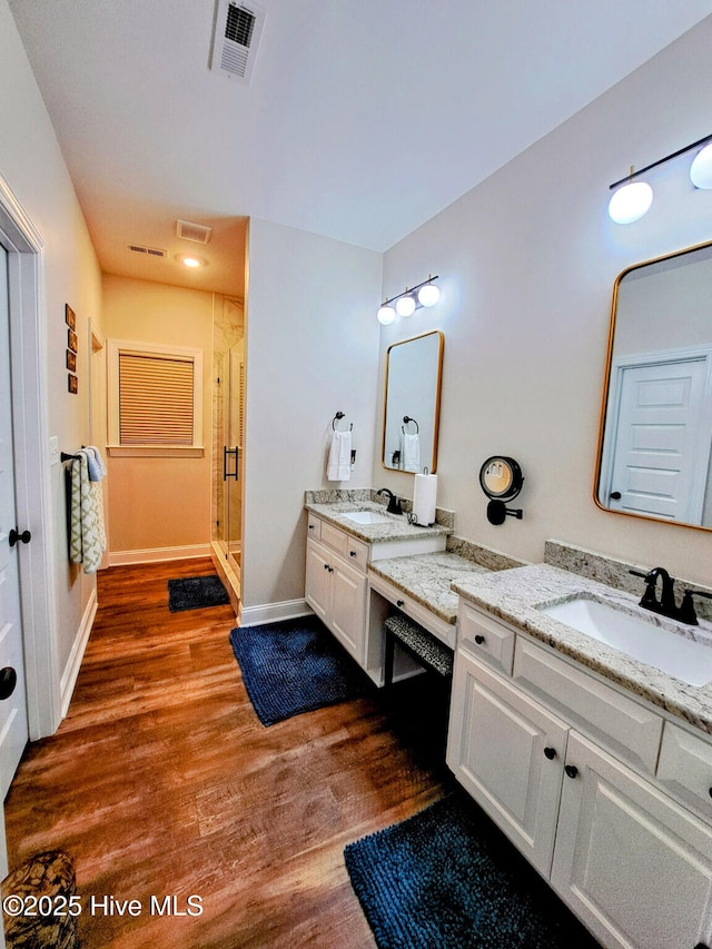 full bath with a shower stall, visible vents, a sink, and wood finished floors