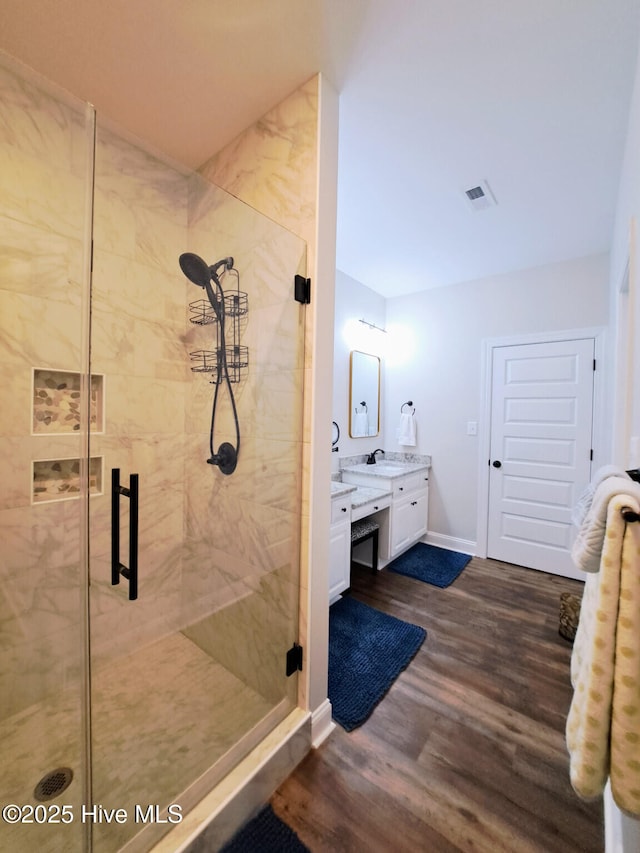 full bathroom featuring wood finished floors, visible vents, baseboards, a shower stall, and vanity