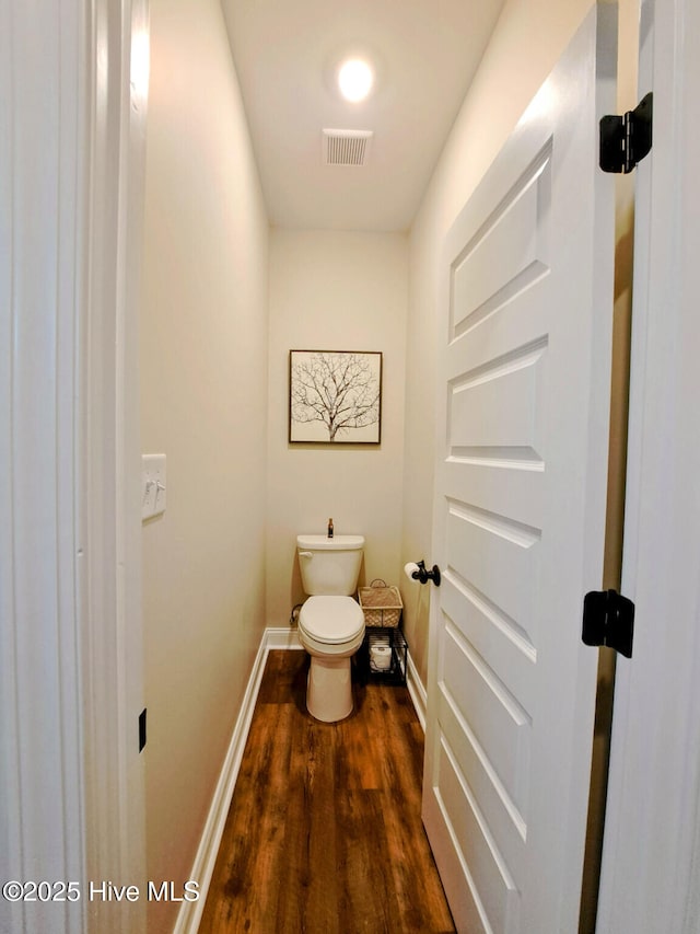 bathroom featuring toilet, visible vents, wood finished floors, and baseboards