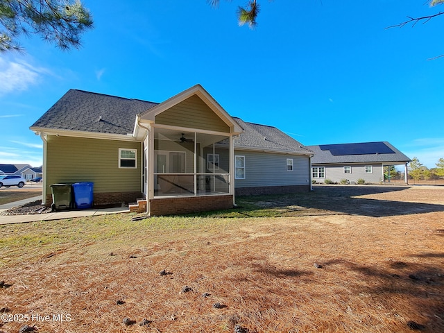 back of house featuring ceiling fan, a sunroom, a shingled roof, and a lawn