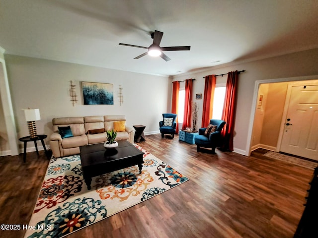 living room with ornamental molding, baseboards, ceiling fan, and dark wood-style floors