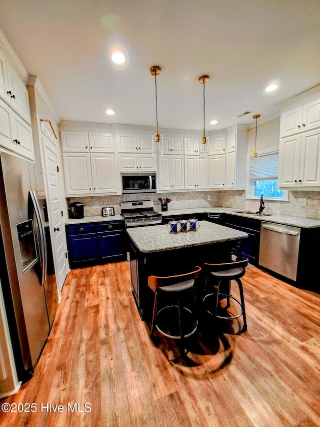 kitchen with white cabinetry, blue cabinets, light wood-style flooring, and appliances with stainless steel finishes
