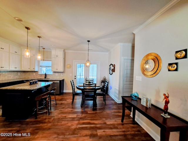 dining area with ornamental molding, baseboards, and dark wood-type flooring