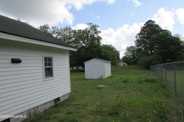 view of yard featuring fence, an outbuilding, and a storage unit
