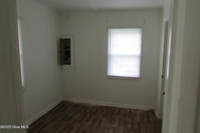 spare room with dark wood-style flooring, baseboards, and electric panel