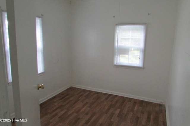 unfurnished room featuring baseboards and dark wood finished floors