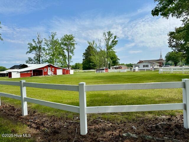 view of yard with a garage, fence, an outbuilding, and a rural view