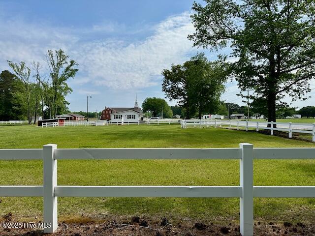 view of gate featuring fence, a yard, and a rural view
