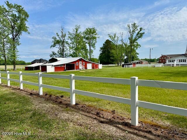 view of yard featuring fence, a detached garage, an outbuilding, a rural view, and an outdoor structure