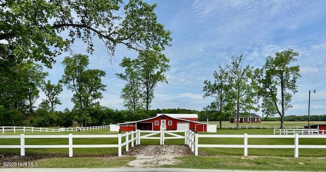 view of yard with a pole building, a rural view, fence, and an outdoor structure