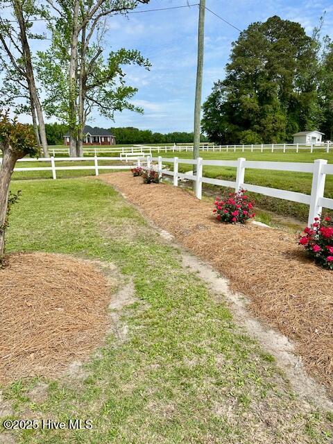 view of yard with fence and a rural view
