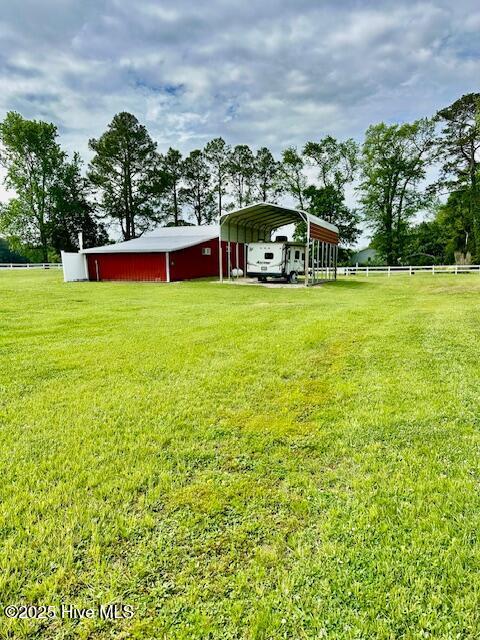 view of yard with fence, an outbuilding, and a carport
