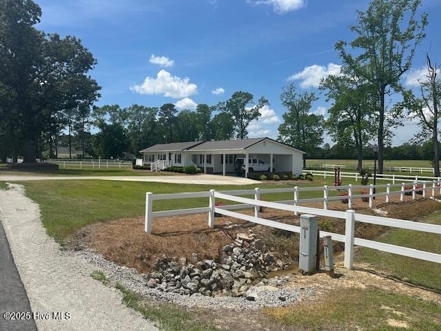 view of front facade featuring fence private yard, driveway, a rural view, and a front yard