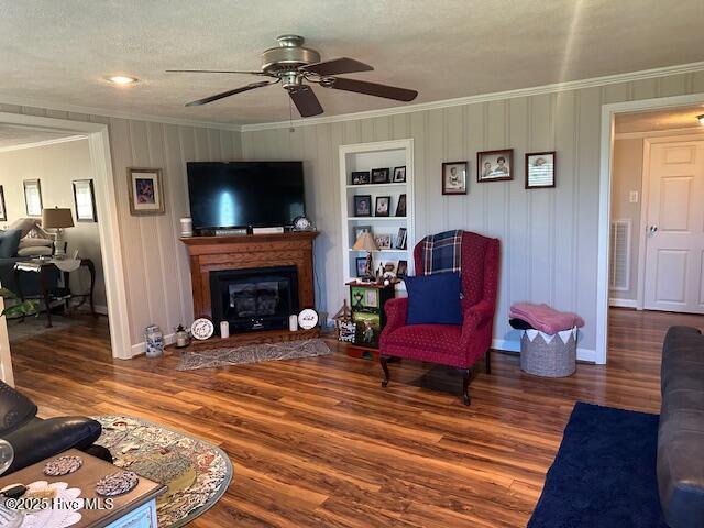 living room with ornamental molding, a ceiling fan, and wood finished floors