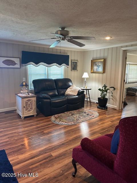 living room with baseboards, ceiling fan, a textured ceiling, and wood finished floors