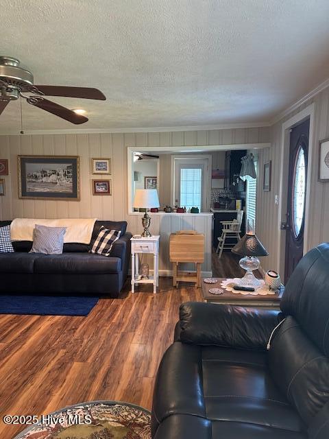 living area with crown molding, a textured ceiling, ceiling fan, and wood finished floors