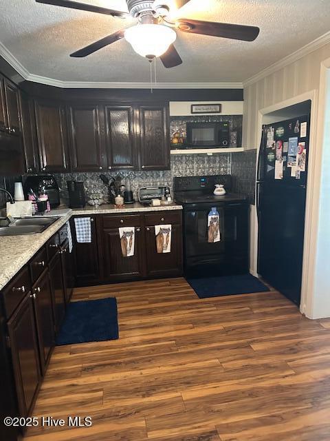 kitchen featuring ceiling fan, a sink, dark wood-type flooring, ornamental molding, and black appliances