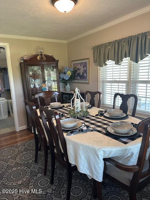 dining area with baseboards, ornamental molding, a textured ceiling, and wood finished floors