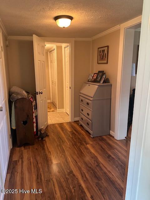 hall with ornamental molding, a textured ceiling, and wood finished floors