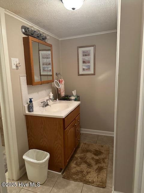 bathroom with crown molding, a textured ceiling, tile patterned floors, and vanity