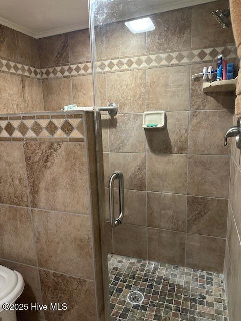full bath featuring ornamental molding and a shower stall