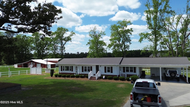 ranch-style home with fence, metal roof, a carport, a front yard, and driveway