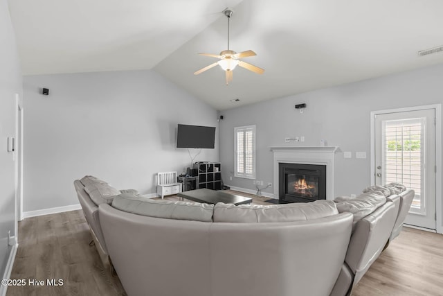 living area featuring a ceiling fan, visible vents, wood finished floors, and vaulted ceiling