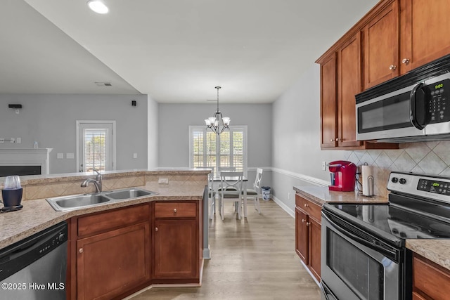 kitchen with a sink, backsplash, a chandelier, and stainless steel appliances