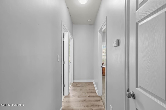 hall featuring baseboards and light wood-style flooring