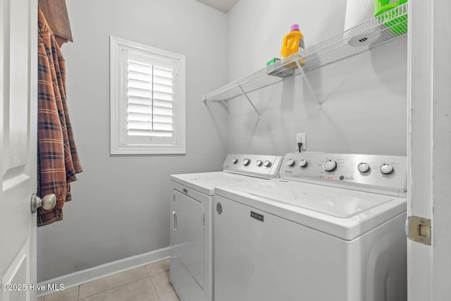 clothes washing area with light tile patterned floors, baseboards, laundry area, and washing machine and dryer