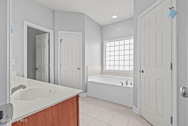 bathroom with tile patterned flooring, baseboards, a garden tub, and vanity