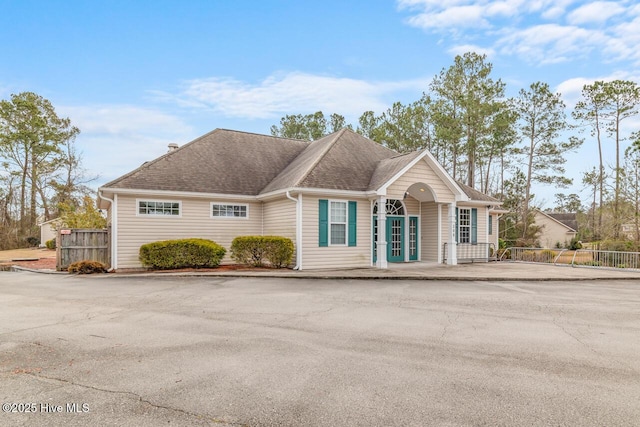 ranch-style home with roof with shingles and fence