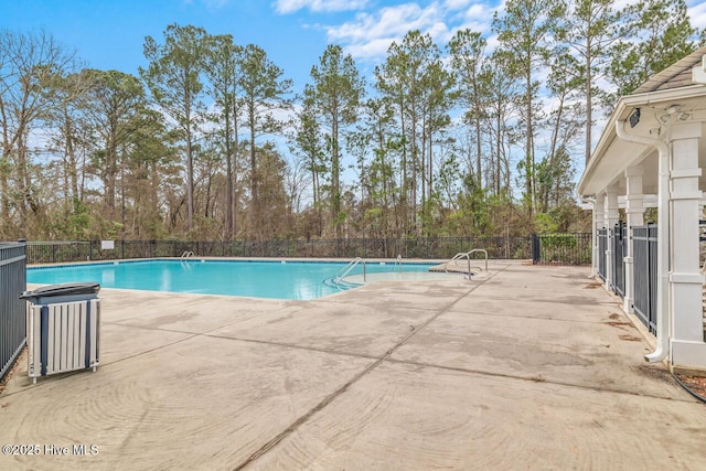pool with a patio area and fence