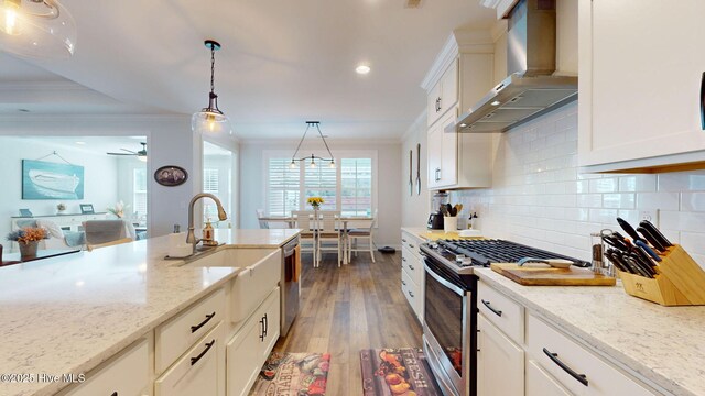 105 Camden Trl, Hampstead, NC 28443 - kitchen with wall chimney range hood, stainless steel appliances, crown molding, hardwood / wood-style floors, and decorative light fixtures