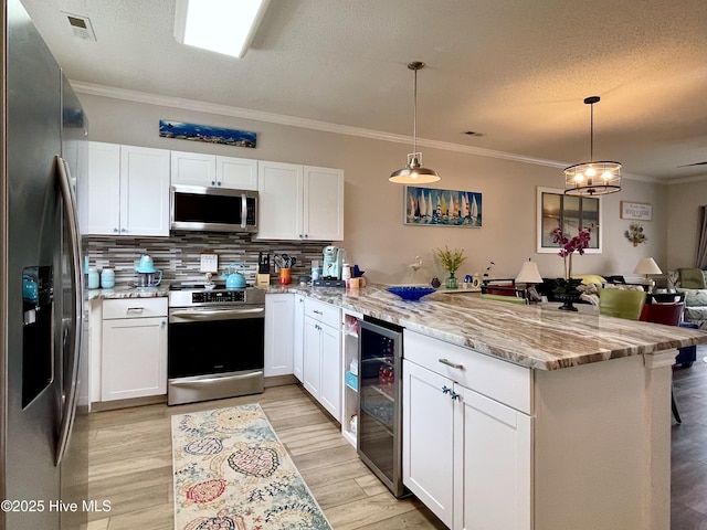 kitchen featuring appliances with stainless steel finishes, a peninsula, white cabinetry, wine cooler, and ornamental molding