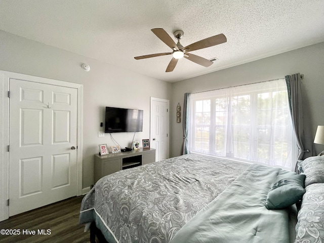 bedroom featuring dark wood-type flooring, a ceiling fan, and a textured ceiling