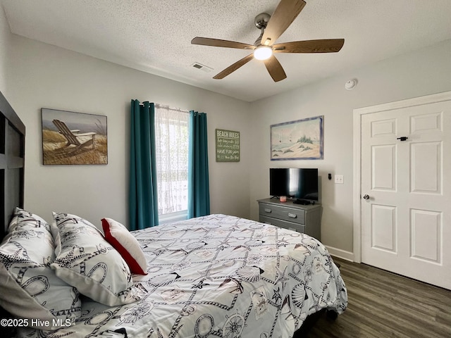 bedroom with dark wood-style flooring, ceiling fan, visible vents, and a textured ceiling