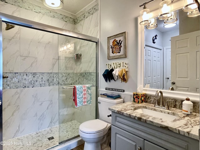 bathroom with vanity, crown molding, toilet, and a shower stall