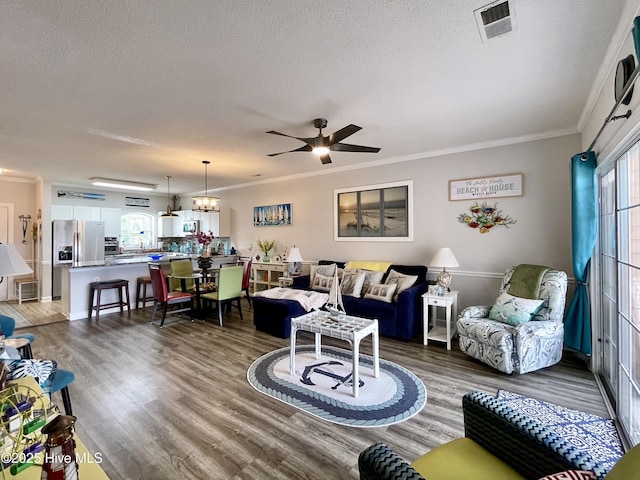 living area with ornamental molding, a ceiling fan, and a textured ceiling