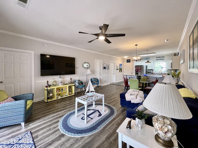 living room with visible vents, ornamental molding, wood finished floors, and ceiling fan with notable chandelier