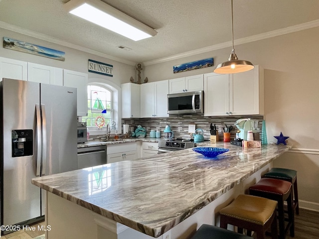 kitchen with backsplash, a peninsula, white cabinets, and appliances with stainless steel finishes