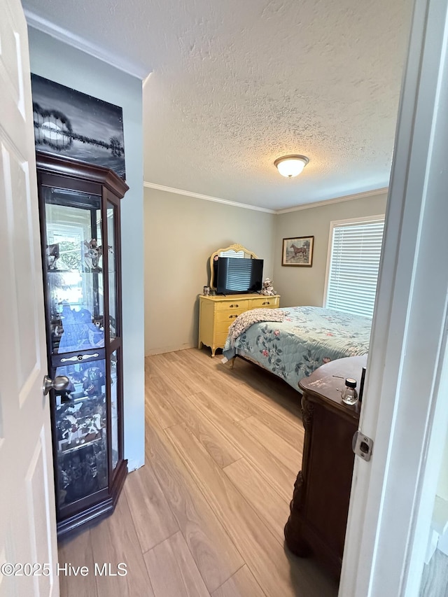 bedroom featuring ornamental molding, a textured ceiling, and wood finished floors