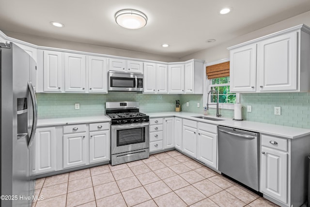 kitchen with stainless steel appliances, a sink, backsplash, light countertops, and white cabinetry