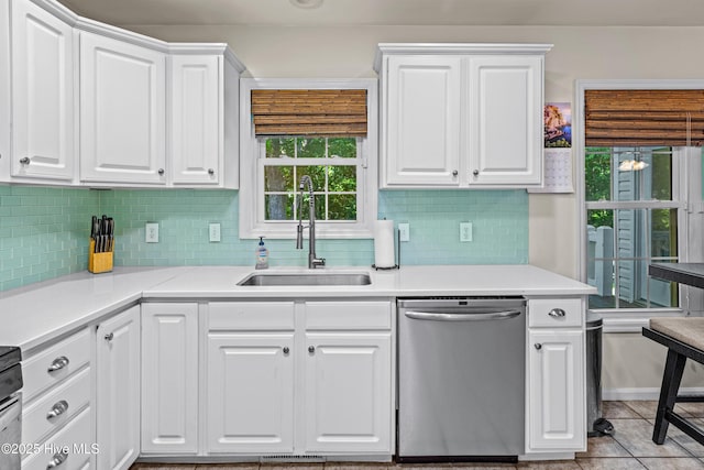 kitchen with stainless steel dishwasher, a sink, backsplash, and white cabinets