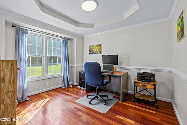 office area with wood-type flooring, a raised ceiling, baseboards, and ornamental molding