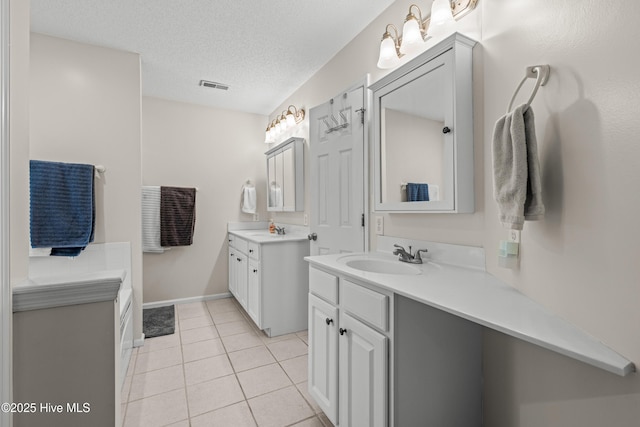 bathroom featuring two vanities, a textured ceiling, tile patterned flooring, and baseboards