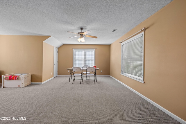 carpeted dining area with ceiling fan, baseboards, and a textured ceiling