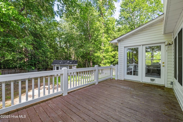 wooden terrace with a shed, an outdoor structure, and view of wooded area